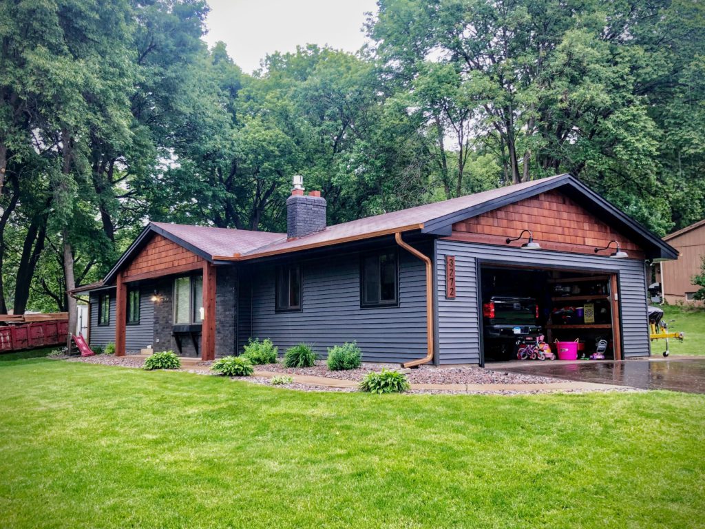 newly-painted house on green hill with wood accent siding